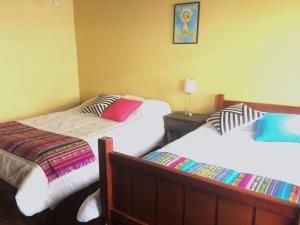 1 dormitorio con 2 camas y mesa con lámpara en Quito Kawsay, en Quito