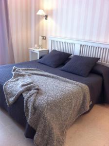ein Bett mit einer blauen Decke und einem Tisch mit einer Lampe in der Unterkunft Convento Tarifa in Tarifa