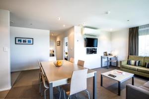 a dining room and living room with a table and chairs at Quest Albany Serviced Apartments in Auckland