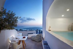 a balcony with a pool and a table and chairs at Callia Caves - Adults Only in Fira
