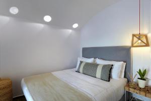 um quarto com uma cama com uma cabeceira cinzenta em Callia Caves - Adults Only em Fira