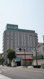 een groot gebouw met een bord erop bij Hotel Route-Inn Ashikaga Ekimae in Ashikaga