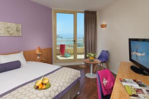 een hotelkamer met een bed en een televisie met een fruitschaal bij Leonardo Plaza Hotel Dead Sea in Ein Bokek