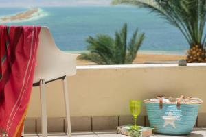 einen weißen Stuhl auf einem Balkon mit Blick auf den Strand in der Unterkunft Leonardo Plaza Hotel Dead Sea in Ein Bokek