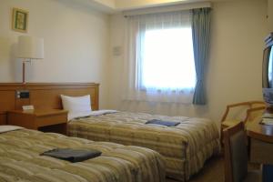 a hotel room with two beds and a window at Hotel Route-Inn Nagaoka Inter in Nagaoka