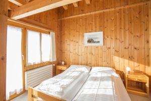 1 dormitorio con 1 cama en una pared de madera en Berghaus Nagens, en Flims