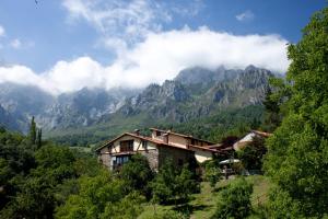 una casa en una colina con montañas al fondo en Posada Las Espedillas, en Camaleño