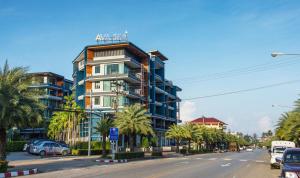 een hoog gebouw in een stadsstraat met palmbomen bij AVA SEA Resort Krabi, Ao Nang Beach in Ao Nang Beach