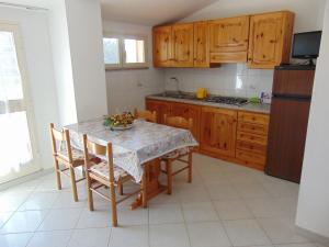 カポリーヴェリにあるAppartamenti Gli Alberiのキッチン(テーブル、椅子付)、キッチン(木製キャビネット付)