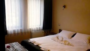 a bedroom with a bed with white sheets and pillows at Family hotel Valchanovata Kashta in Fotinovo