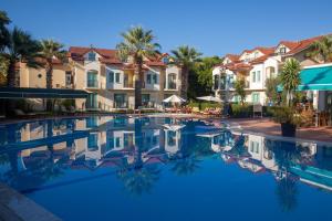 フェティエにあるRebin Beach Hotelのヤシの木と家があるリゾートのスイミングプールを利用できます。
