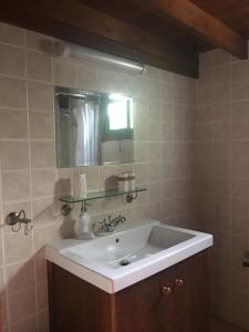 een badkamer met een witte wastafel en een spiegel bij Koilani Village House in Koilani