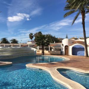 a swimming pool in a resort with palm trees at Denia Playa I in Denia