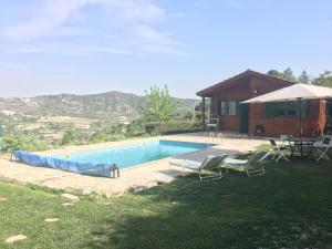 a swimming pool with chairs and a house with mountains at Koilani Village House in Koilani