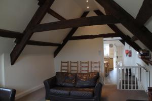 a living room with a leather couch and wooden beams at Old Court Hotel & Apartments in Symonds Yat