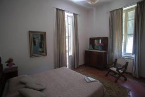 a bedroom with a bed and a chair and two windows at Villa Daura in Riccò del Golfo di Spezia