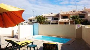 - une piscine avec 2 chaises et un parasol dans l'établissement Holiday House, à Albufeira