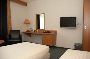 Habitación de hotel con cama, escritorio y TV. en Fletcher Hotel - Restaurant Steenwijk, en Steenwijk