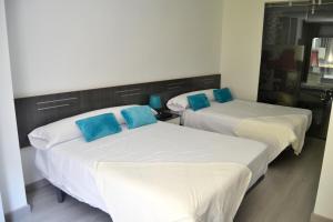 Dos camas en una habitación con almohadas azules. en Bed&Breakfast 10 GIRONA, en Girona