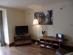 sala de estar con TV y mesa con lámpara en Pillarbox Cottage en Matlock
