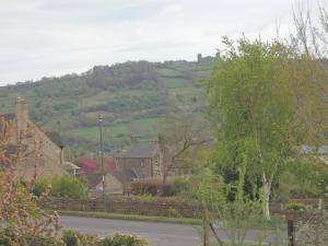 a village with houses and a hill in the distance at Pillarbox Cottage in Matlock