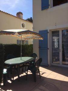 ein Tisch und Stühle mit einem Sonnenschirm auf einer Terrasse in der Unterkunft Maison vacances Noirmoutier Barbatre in Barbâtre
