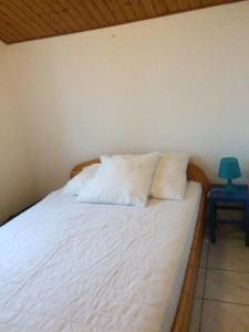 ein Bett mit weißer Bettwäsche und einer blauen Lampe auf dem Tisch in der Unterkunft Maison vacances Noirmoutier Barbatre in Barbâtre