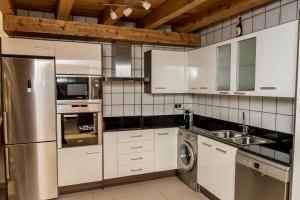 a kitchen with white cabinets and a stainless steel refrigerator at Plaza Apartamentos in Binéfar