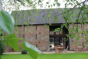 a brick building with a patio with tables and chairs at Old Court Hotel & Apartments in Symonds Yat