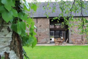 a brick building with chairs and tables in the yard at Old Court Hotel & Apartments in Symonds Yat