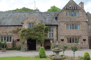 an old stone hotel with a fountain in front of it at Old Court Hotel & Apartments in Symonds Yat