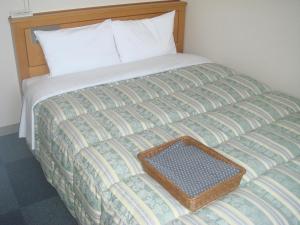 a bed with a wooden headboard and a basket on it at Hotel Route-Inn Fukui Owada in Fukui