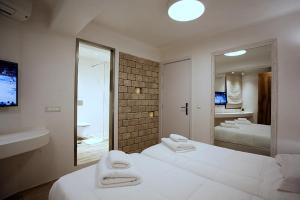 a bedroom with two white beds and a mirror at Anagram Hotel in Mikonos