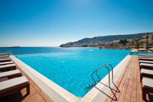 een groot zwembad met stoelen en het water bij Alimounda Mare Hotel in Karpathos