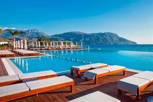 a swimming pool with lounge chairs and the water at Alimounda Mare Hotel in Karpathos