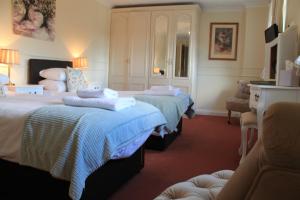a hotel room with two beds and a chair at Old Court Hotel & Apartments in Symonds Yat