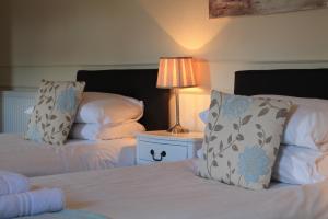 a bedroom with two beds and a lamp on a table at Old Court Hotel & Apartments in Symonds Yat