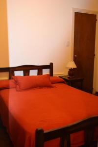 a bedroom with a bed with an orange blanket at Hotel Cristal in Tandil