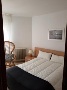 a bedroom with a large bed and a chair at Apartament a la Placeta de Sant Joan 21, 3r in Sant Feliu de Guixols