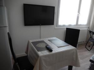 a room with a table with a television on a wall at Le Studio Sam in Illkirch-Graffenstaden