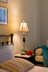 a bedroom with a bed and a lamp and a chair at Antouanetta Apartments in Ermoupoli