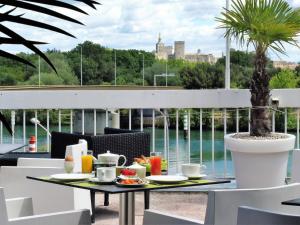 a table with food on a balcony with a palm tree at O'Cub Hotel in Villeneuve-lès-Avignon