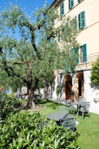 einen Tisch und Stühle in einem Garten mit einem Baum in der Unterkunft Hotel Tiziana Garnì in Gargnano