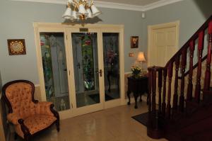 a hallway with a staircase with glass doors and a chair at Killererin House B&B in Letterkenny