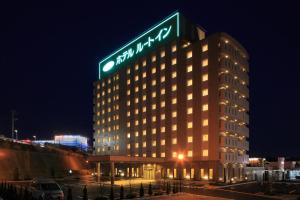 Hotel Route-Inn Sendaiizumi Inter في سيندايْ: مبنى عليه علامة في الليل