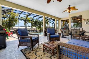 a screened in porch with chairs and a bed at Villa Maxine in Cape Coral