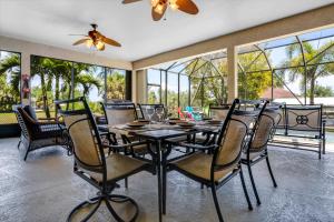 a dining room with a table and chairs and windows at Villa Maxine in Cape Coral