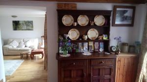 a living room with a wooden cabinet with plates on it at The Old Swan in Cold Ashton