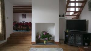 uma sala de estar com televisão e um vaso de flores em The Old Swan em Cold Ashton