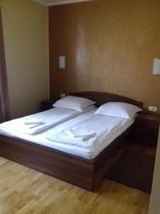 a large bed with white sheets and pillows on it at Pensiunea Damiris in Baile Felix